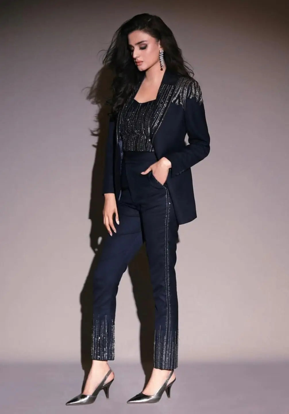 A woman wearing the stardust three-piece power suit in dark navy with shimmering silver sequin detailing defines modern luxury