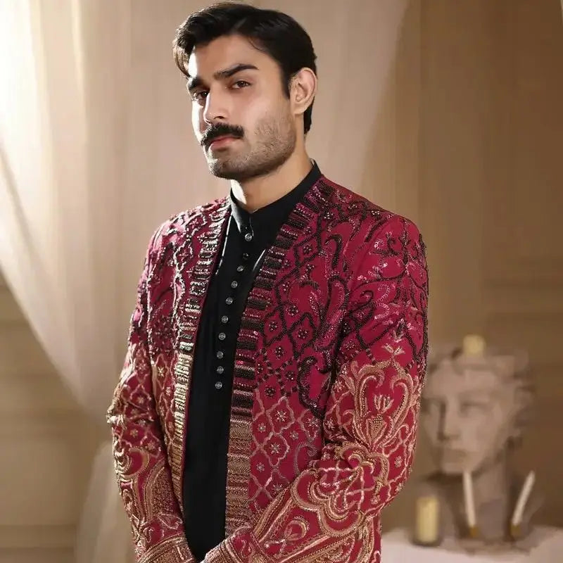 A richly embroidered crimson and gold men’s formal jacket with intricate sequin detailing by Thakur Singh