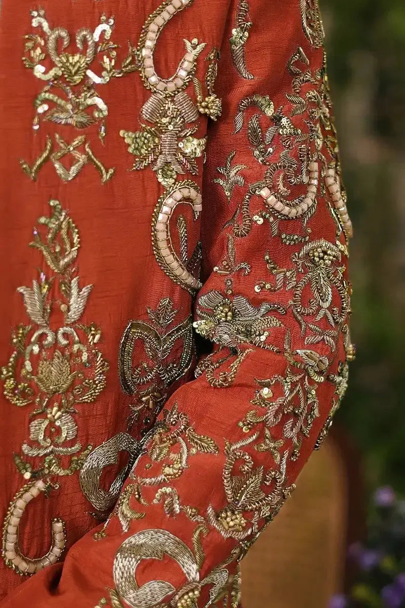 Wazir khan rich rust-colored fabric with intricate gold and silver thread embroidery featuring floral and paisley motifs