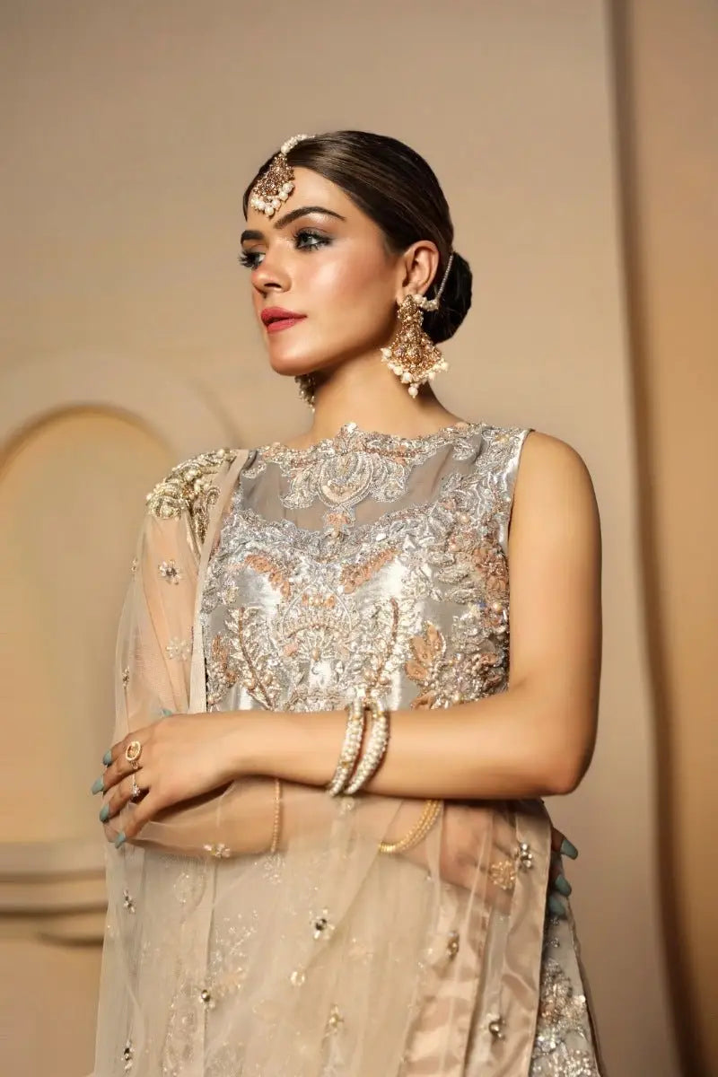 A woman wears a sleeveless silver and gold embroidered top with sheer embellished fabric from ZARRIN by ahsan tariq raqeeb se edit